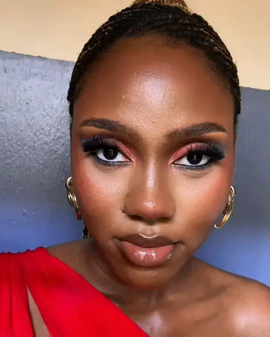 Red-toned smoky eyes on a woman in a red one-shoulder dress
